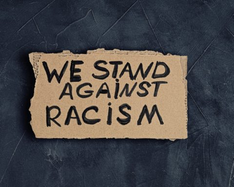 We stand against racism text on cardboard on dark background