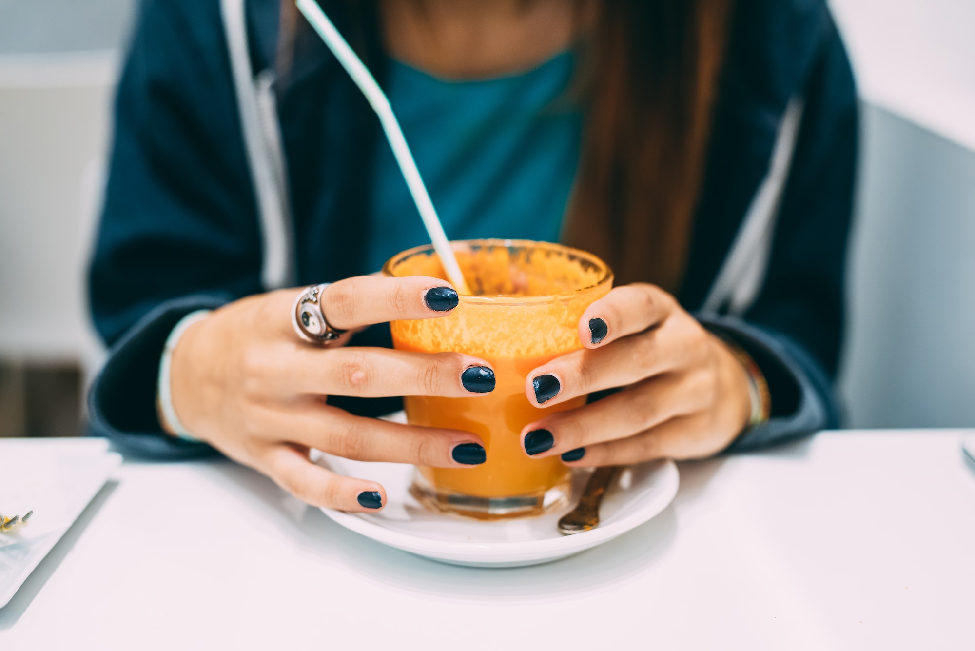 Close up on the hands of a young woman holding a glass of juice - health, break, relaxing concept